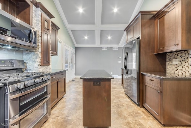 kitchen featuring backsplash, dark stone countertops, appliances with stainless steel finishes, a kitchen island, and ornamental molding