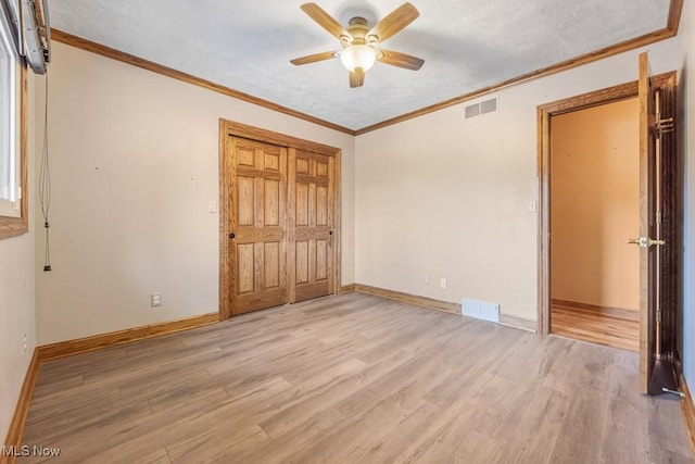 unfurnished bedroom with ceiling fan, light hardwood / wood-style flooring, a textured ceiling, a closet, and ornamental molding