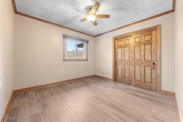 unfurnished bedroom with light wood-type flooring, ornamental molding, a textured ceiling, ceiling fan, and a closet