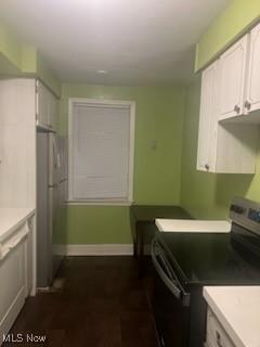 kitchen featuring range with electric cooktop, white cabinetry, and fridge