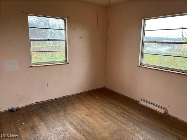 spare room with hardwood / wood-style floors, a baseboard radiator, and a wealth of natural light