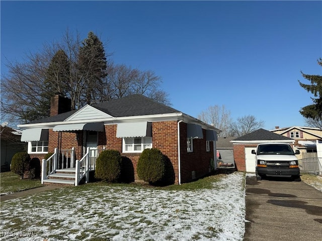 bungalow featuring a garage and an outbuilding