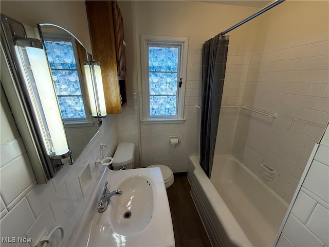 full bathroom with sink, tile walls, toilet, and shower / bathtub combination with curtain