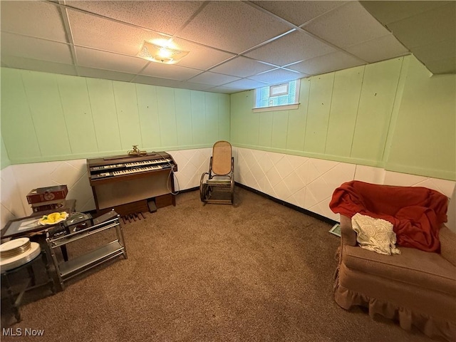 living area featuring carpet floors and a paneled ceiling