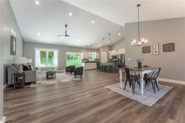 dining space featuring ceiling fan with notable chandelier, dark hardwood / wood-style flooring, and high vaulted ceiling