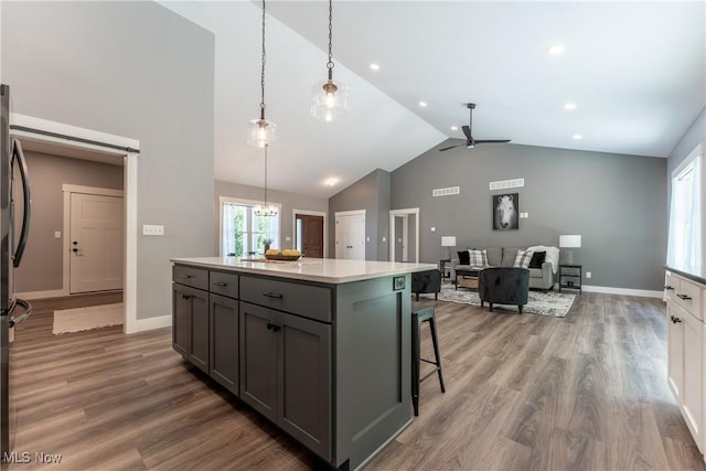 kitchen featuring gray cabinetry, dark wood-type flooring, ceiling fan with notable chandelier, decorative light fixtures, and a kitchen island