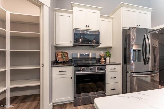 kitchen featuring dark stone countertops, dark hardwood / wood-style flooring, white cabinets, and stainless steel appliances