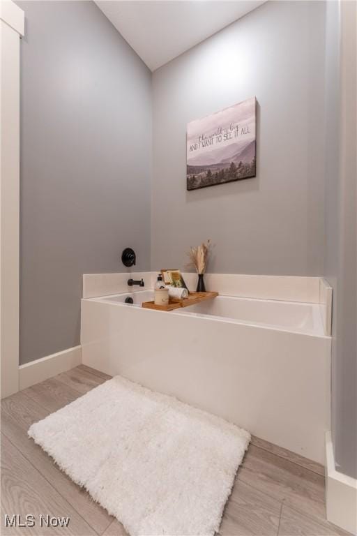 bathroom with a tub and hardwood / wood-style flooring