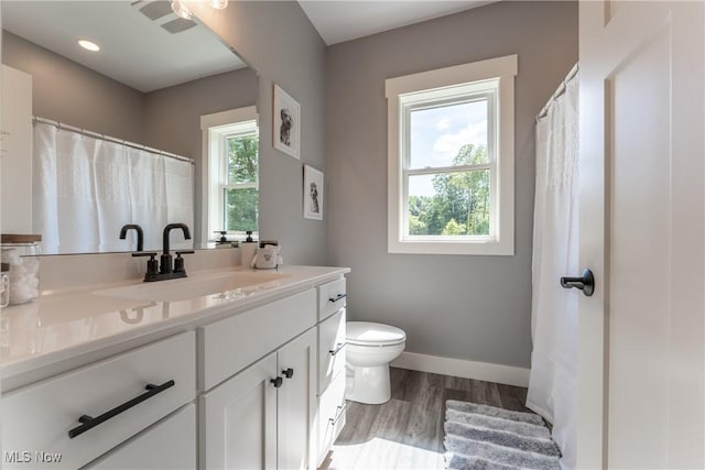 bathroom with hardwood / wood-style flooring, vanity, toilet, and a wealth of natural light