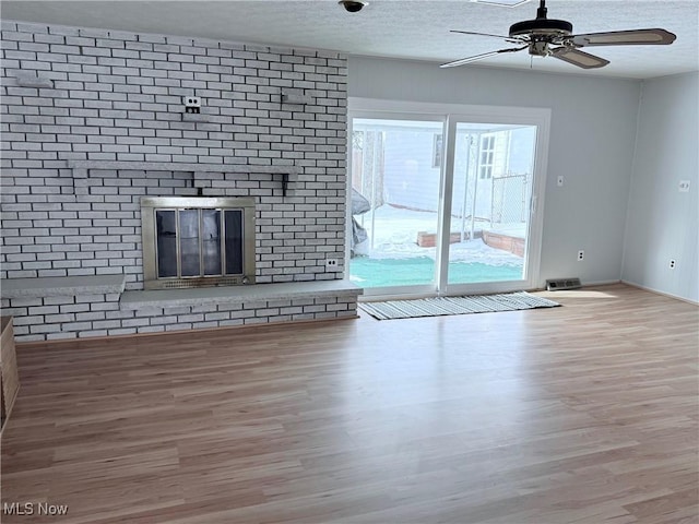 unfurnished living room with hardwood / wood-style flooring, ceiling fan, a textured ceiling, and a fireplace