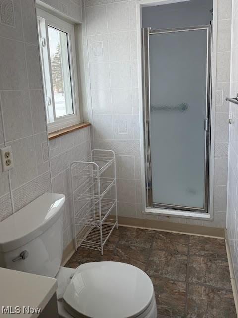 bathroom with vanity, toilet, tile walls, and walk in shower