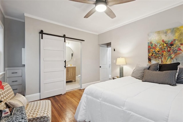 bedroom featuring ensuite bathroom, ceiling fan, a barn door, ornamental molding, and wood-type flooring