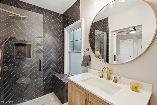 bathroom with tiled shower, vanity, and ceiling fan