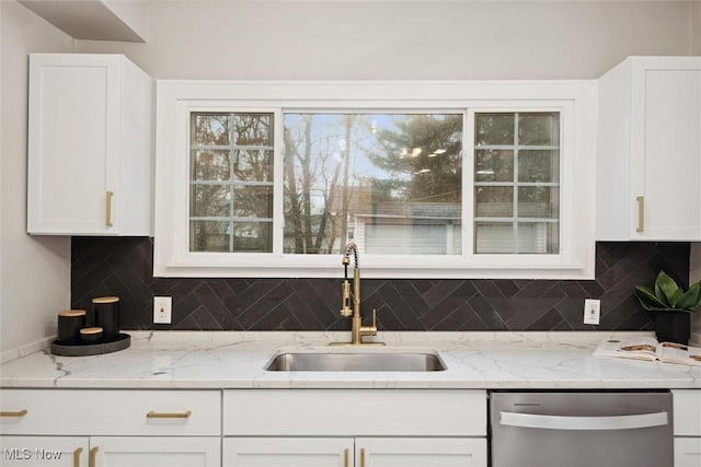 kitchen with white cabinets, stainless steel dishwasher, light stone countertops, and sink