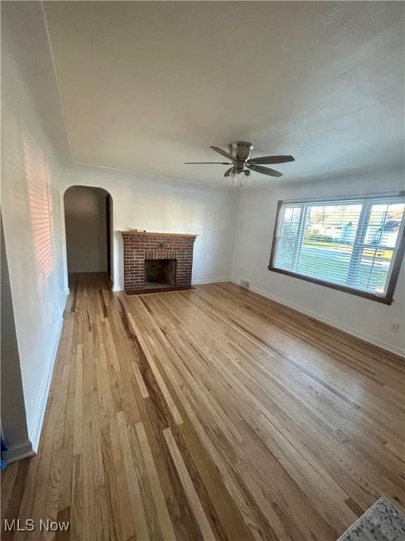 unfurnished living room with ceiling fan, a fireplace, and light hardwood / wood-style floors