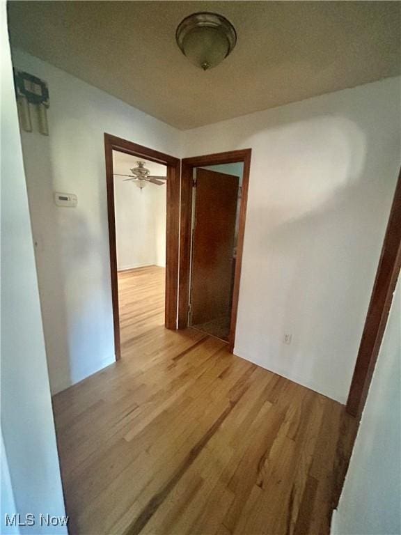 corridor with a textured ceiling and light hardwood / wood-style flooring