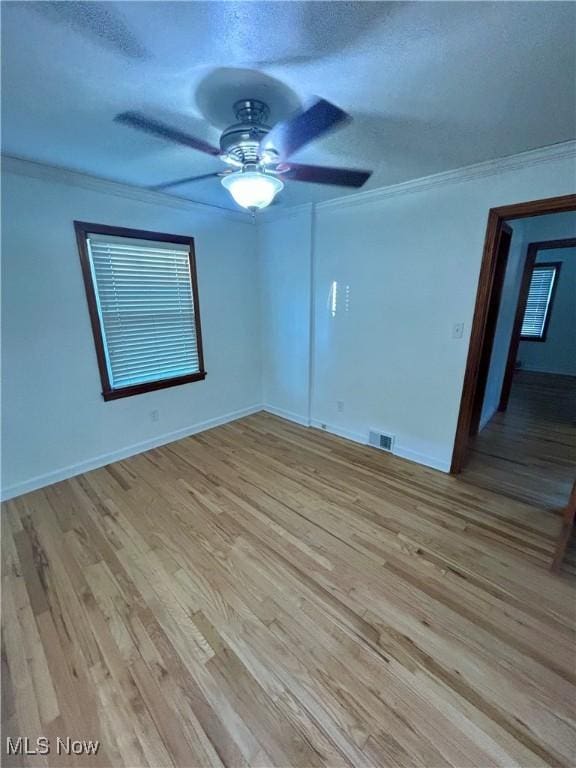 empty room with ceiling fan, light hardwood / wood-style floors, ornamental molding, and a textured ceiling