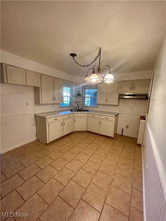 kitchen with decorative backsplash, sink, hanging light fixtures, and an inviting chandelier