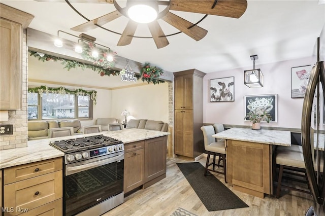 kitchen with tasteful backsplash, light hardwood / wood-style floors, decorative light fixtures, a breakfast bar area, and appliances with stainless steel finishes