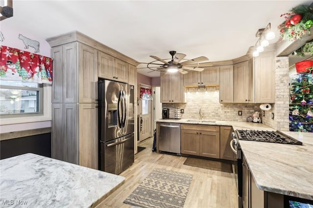 kitchen with ceiling fan, sink, stainless steel appliances, decorative backsplash, and light wood-type flooring