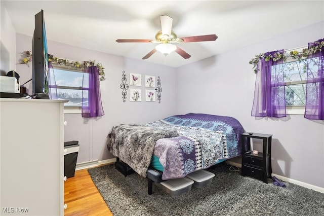 bedroom with multiple windows, ceiling fan, and wood-type flooring