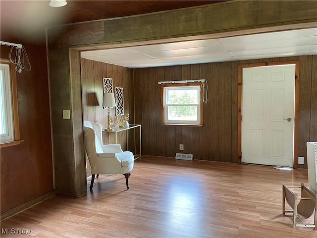 unfurnished room featuring wooden walls and light hardwood / wood-style flooring