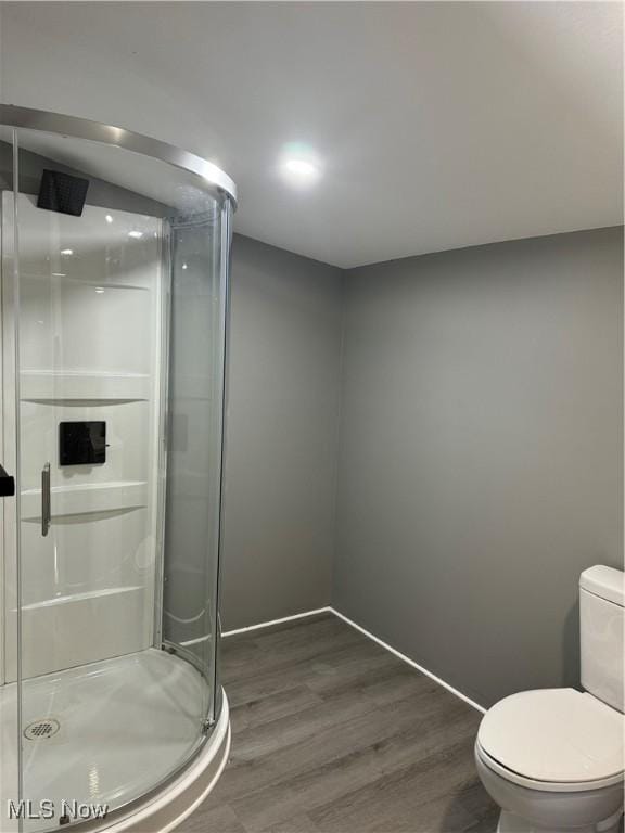 bathroom featuring hardwood / wood-style flooring, toilet, and a shower with door