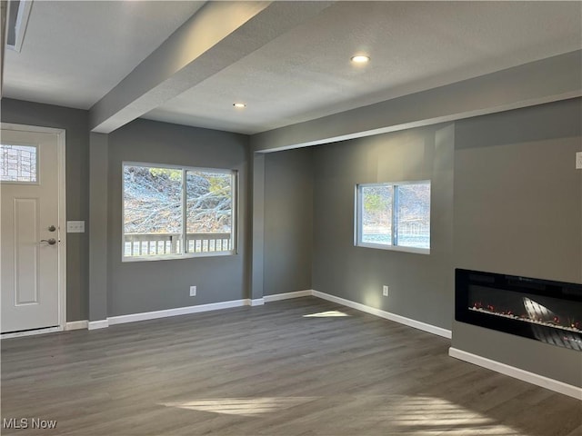 unfurnished living room with a healthy amount of sunlight and dark hardwood / wood-style floors