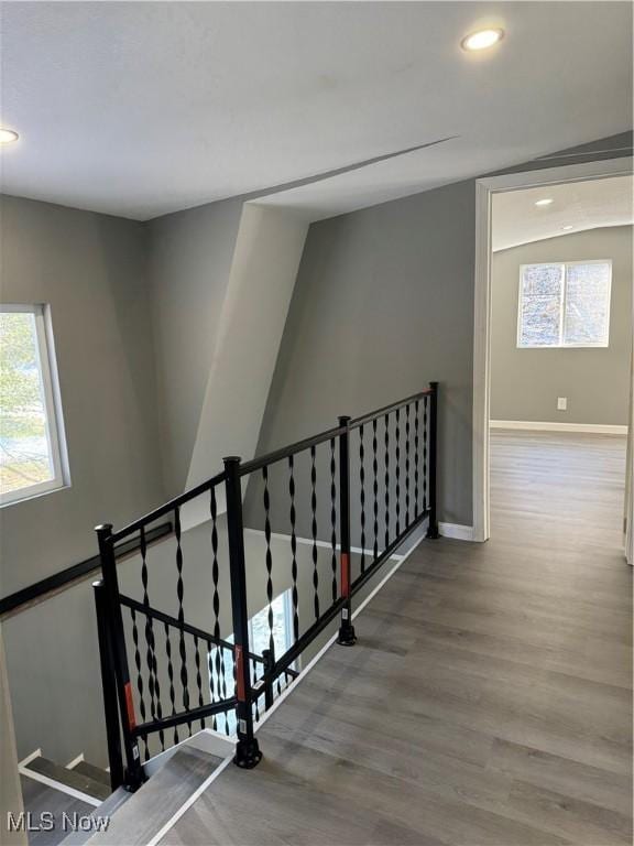 staircase featuring hardwood / wood-style floors, vaulted ceiling, and plenty of natural light