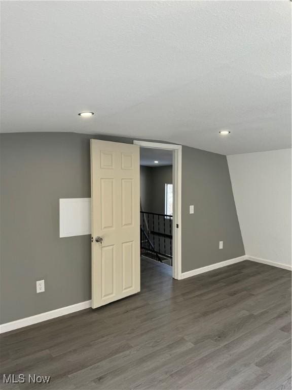 unfurnished room featuring dark wood-type flooring and vaulted ceiling