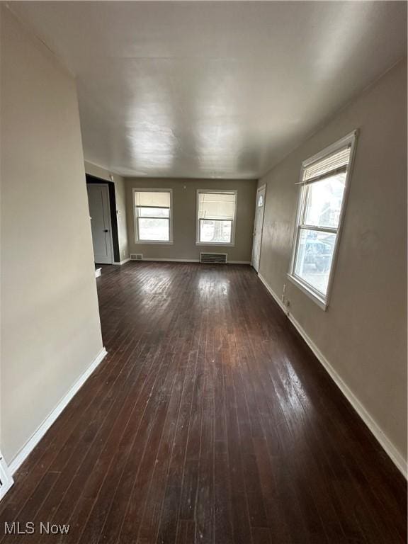 unfurnished living room featuring dark wood-type flooring and a wealth of natural light