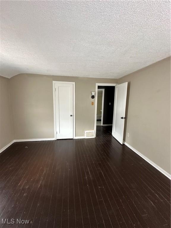 spare room with a textured ceiling and dark wood-type flooring