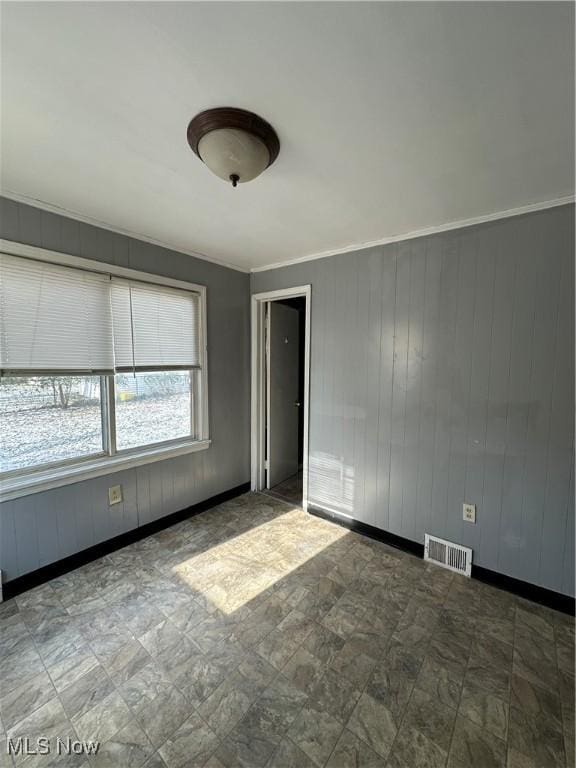 unfurnished room featuring wood walls and crown molding