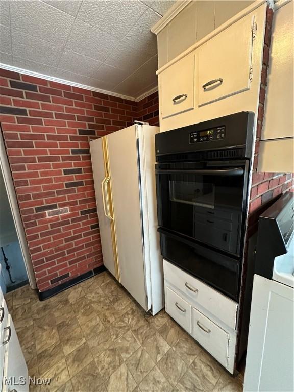 kitchen with white fridge, double oven, and brick wall