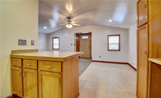 kitchen with kitchen peninsula, ceiling fan, tile countertops, and vaulted ceiling