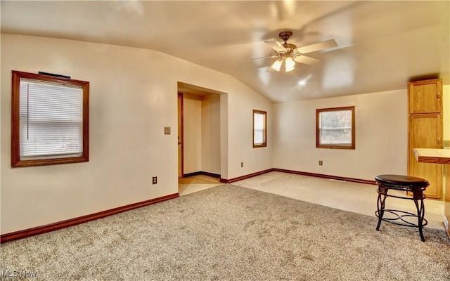 unfurnished living room with ceiling fan, light colored carpet, and lofted ceiling