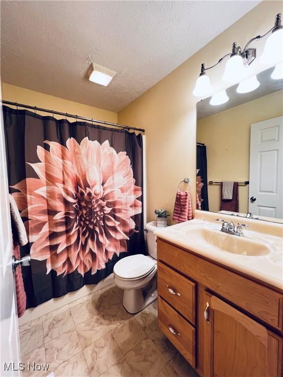 bathroom with vanity, toilet, and a textured ceiling