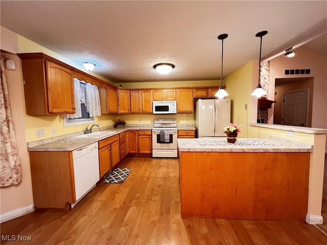 kitchen featuring sink, kitchen peninsula, decorative light fixtures, white appliances, and light wood-type flooring