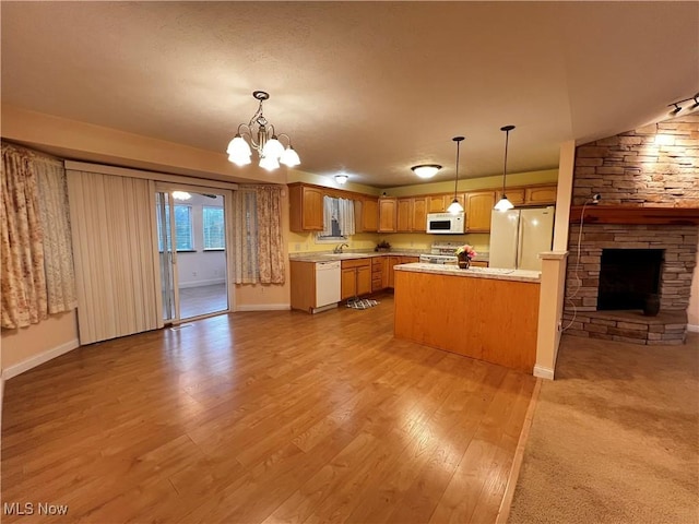 kitchen with white appliances, a chandelier, a fireplace, light hardwood / wood-style floors, and hanging light fixtures