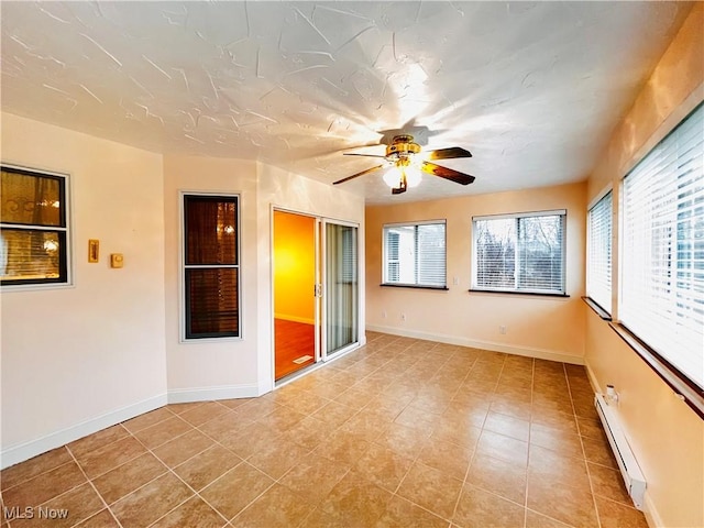 tiled spare room with a wealth of natural light, ceiling fan, and a baseboard radiator