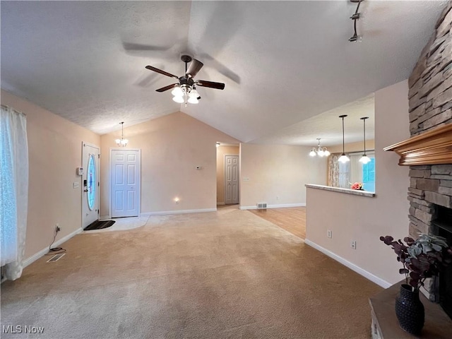 unfurnished living room with a fireplace, ceiling fan with notable chandelier, light colored carpet, and vaulted ceiling