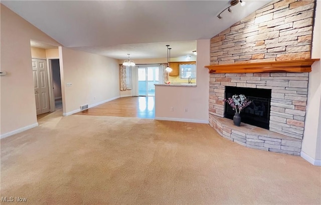 unfurnished living room with track lighting, a fireplace, light carpet, and vaulted ceiling