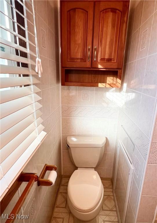 bathroom featuring toilet and tile walls