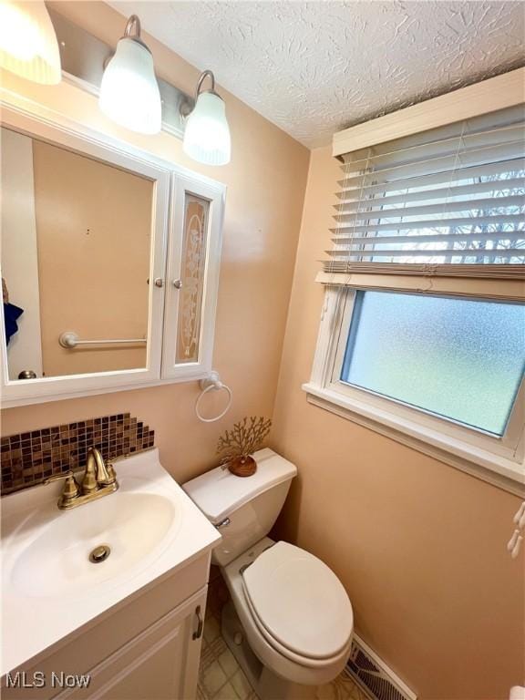 bathroom with backsplash, vanity, toilet, and a textured ceiling