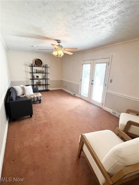 living area with carpet, french doors, ceiling fan, ornamental molding, and a textured ceiling