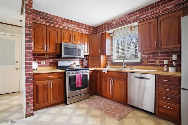 kitchen with tasteful backsplash, sink, stainless steel appliances, and brick wall