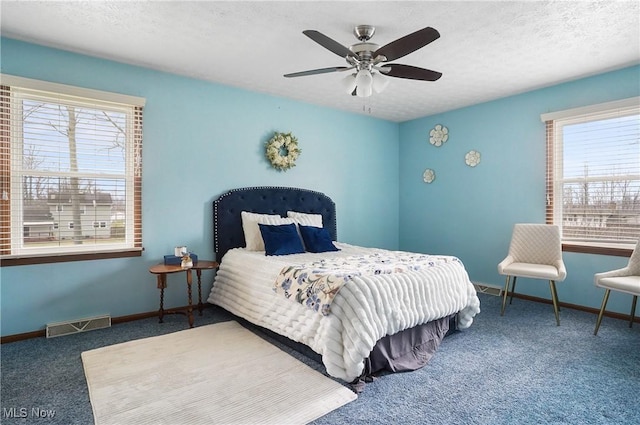 carpeted bedroom with ceiling fan and a textured ceiling