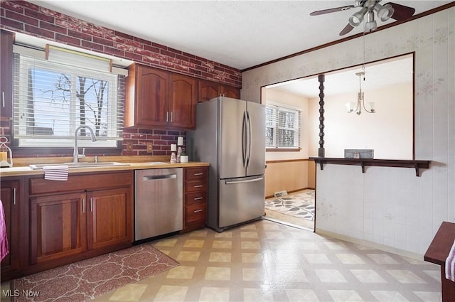 kitchen with hanging light fixtures, ceiling fan with notable chandelier, sink, and appliances with stainless steel finishes