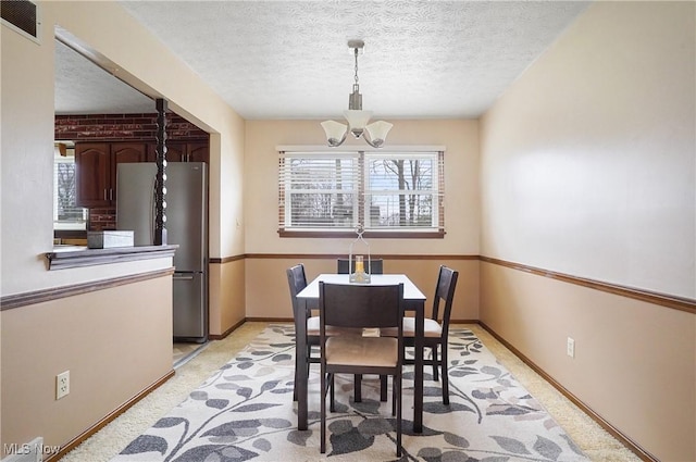 carpeted dining space with a textured ceiling and a notable chandelier