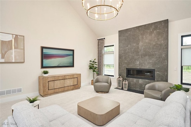 carpeted living room with a high end fireplace, a chandelier, and high vaulted ceiling